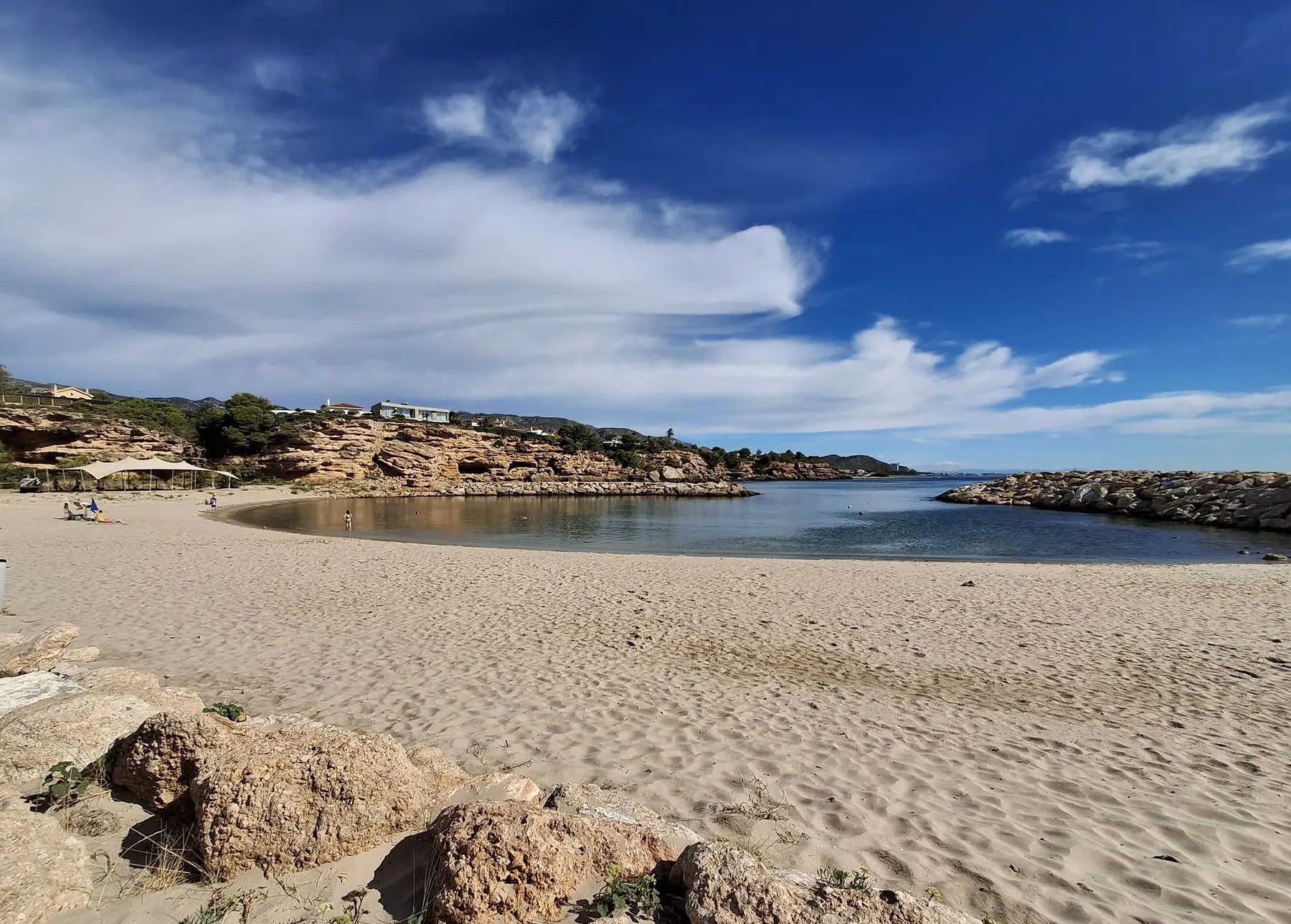 Arena y agua en la playa de Calafat, con el espigón al fondo
